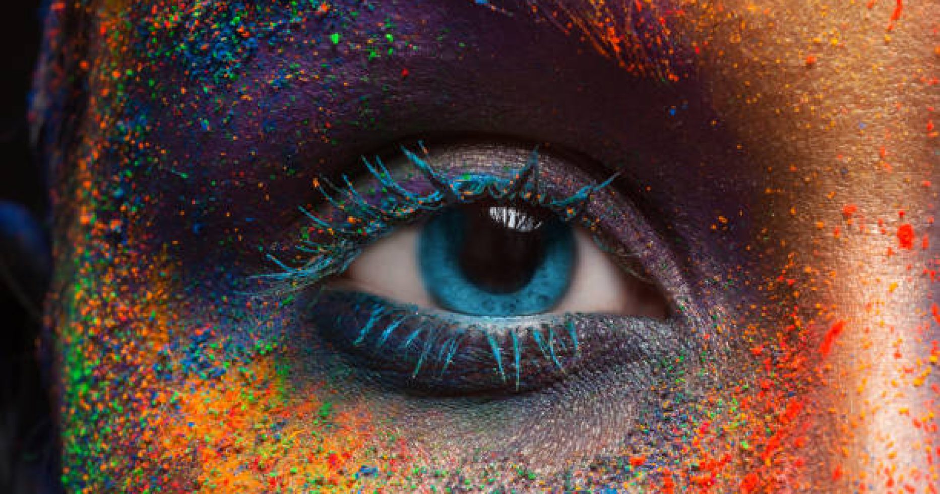 Crop of female eye with colorful make up. Beautiful fashion model with creative art makeup. Abstract colourful splash make-up. Holi festival
